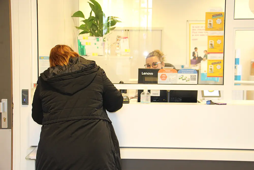 Dame de dos écrivant sur le comptoir de l'agence postale